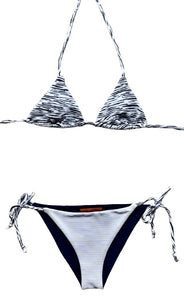 Bikini de cortina de tejido con estructura estampado a rayas blanco y negro. Braguita por delante blanca con tejido de canalé con lurex plata y por detrás del mismo tejido que la parte de arriba.