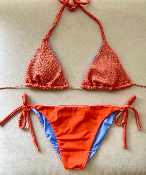 Bikini de cortina de estructura naranja con metalizado. La braguita es naranja liso por delante y del tejido con estructura como la parte de arriba por detrás.