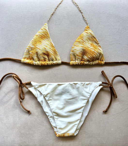 Bikini de cortina de tejido con estampado amarillento con estructura y lurex. &nbsp;Braguita por delante blanca y por detrás del mismo tejido que la parte de arriba.