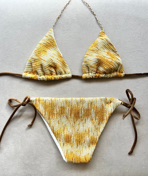 Bikini de cortina de tejido con estampado amarillento con estructura y lurex. &nbsp;Braguita por delante blanca y por detrás del mismo tejido que la parte de arriba.